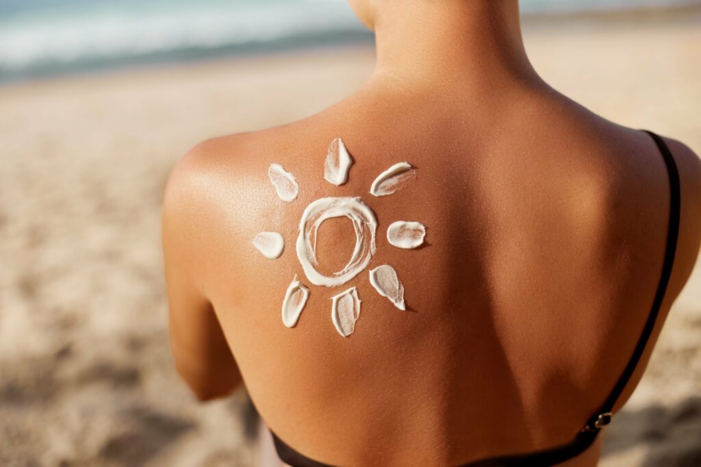 Sunscreen applied to woman's back for skin cancer prevention.